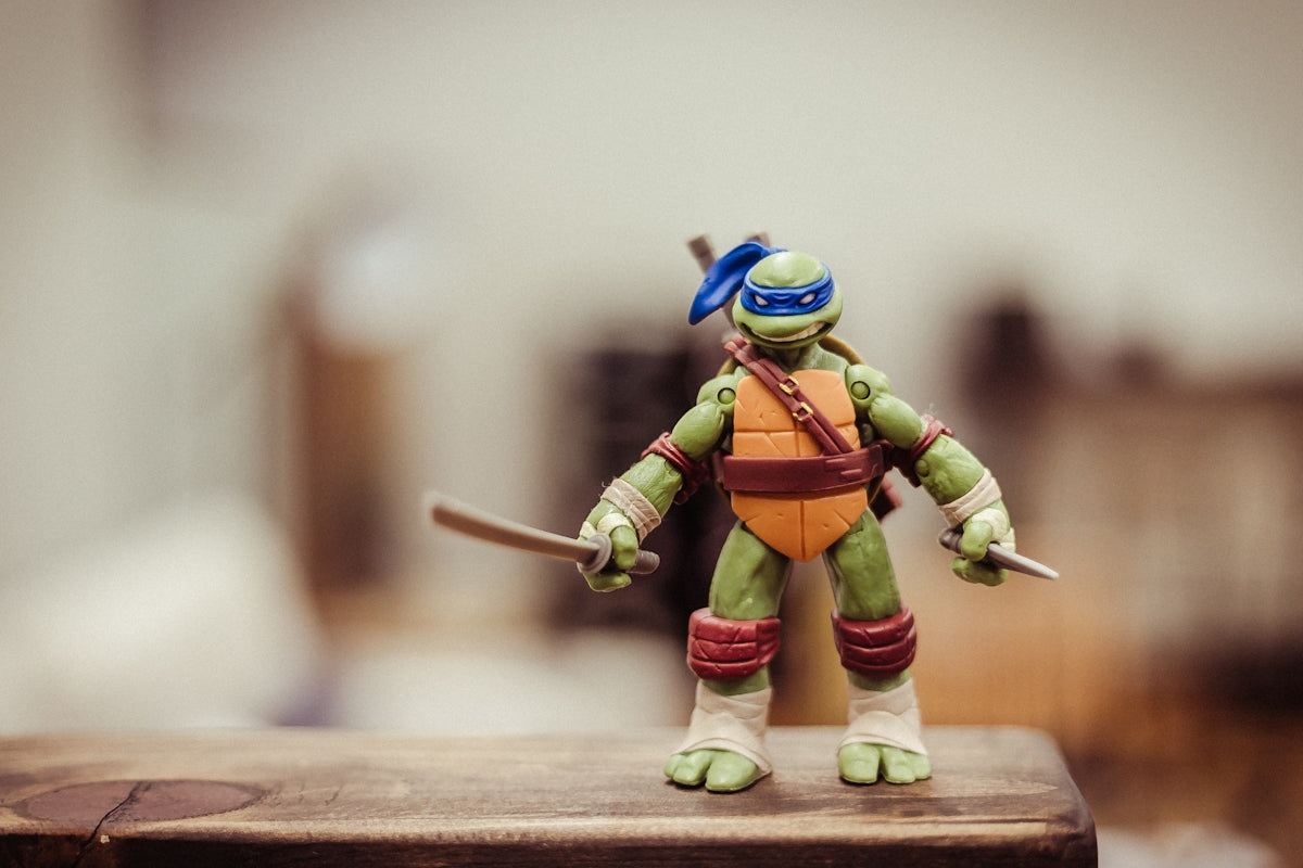 selective focus photography of TMNT Leonardo action figure on brown wooden surface