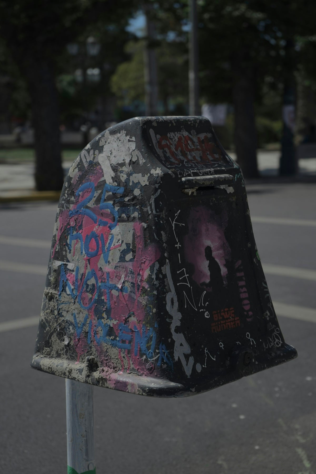 a mailbox covered in graffiti sitting on the side of a road