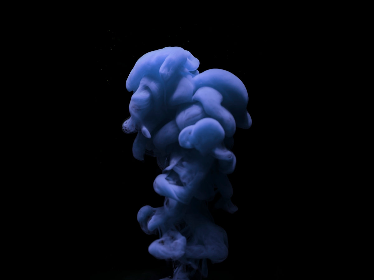 a blue substance floating in the air on a black background