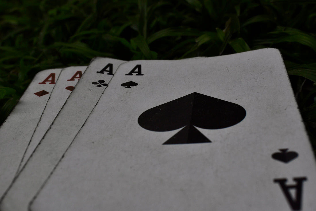 four playing cards sitting on the ground in the grass