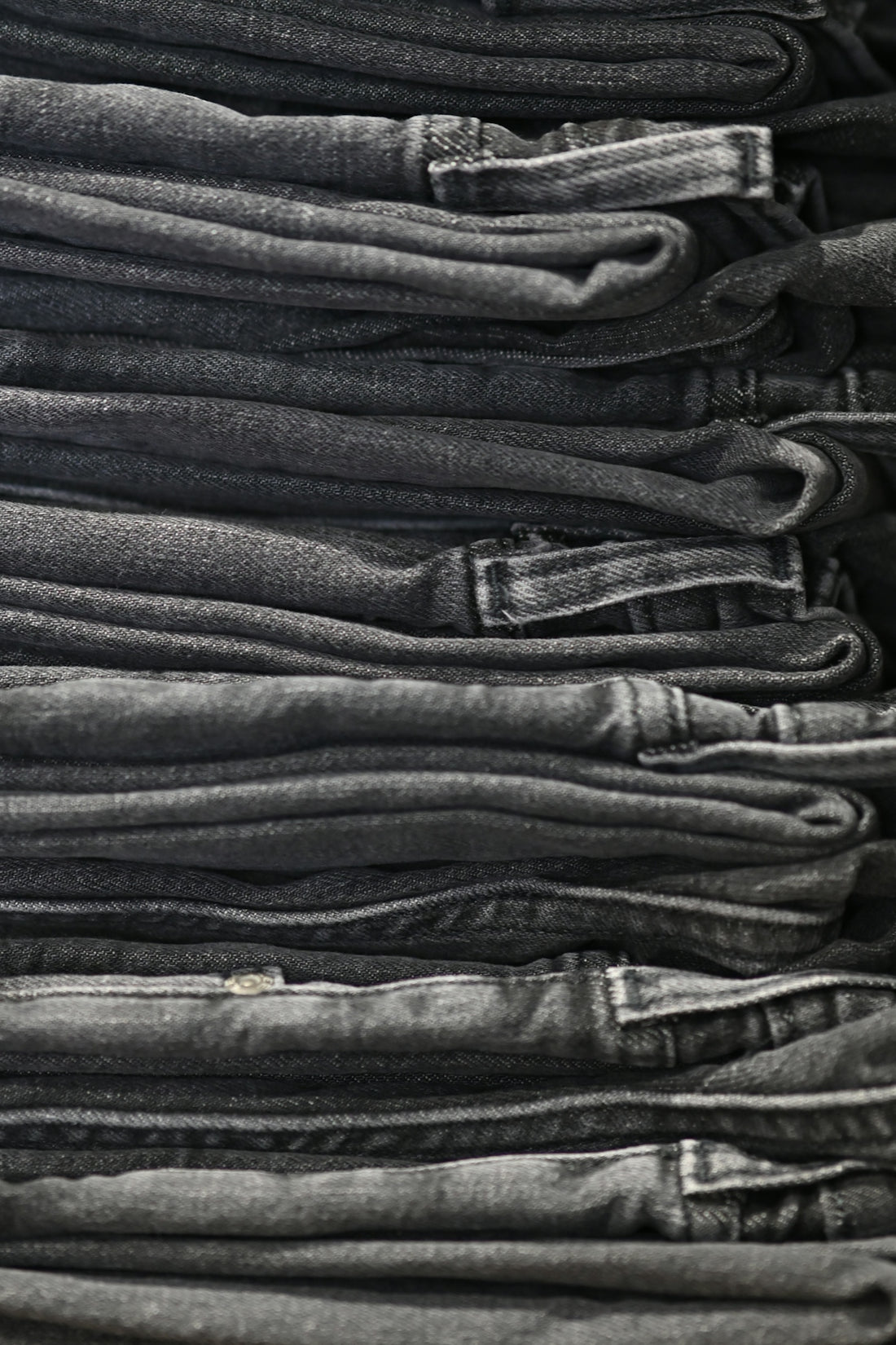 a pile of black jeans stacked on top of each other