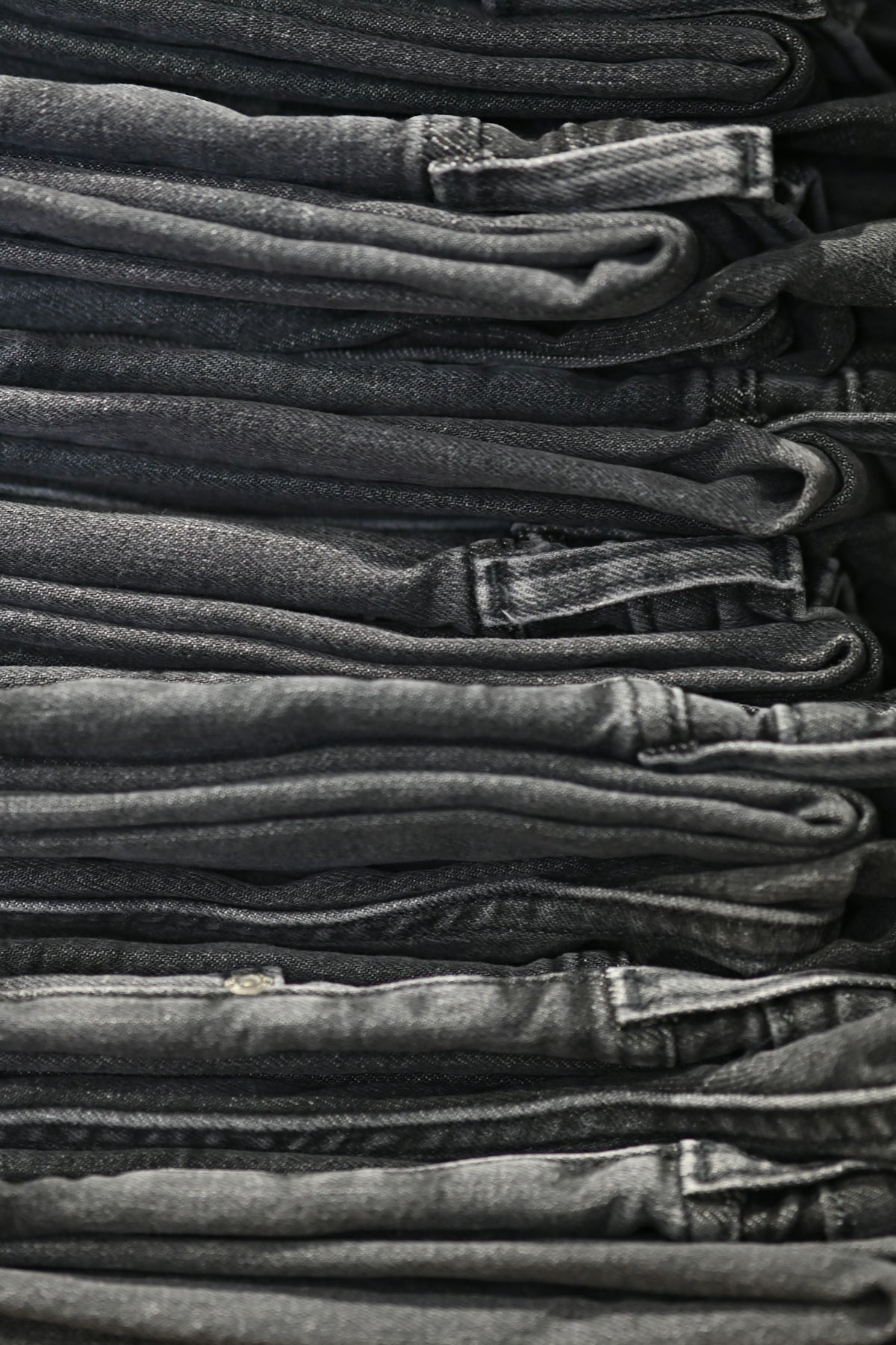 a pile of black jeans stacked on top of each other