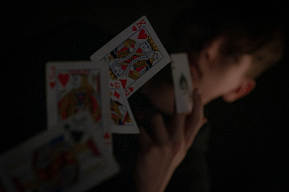 a person holding up playing cards in the dark