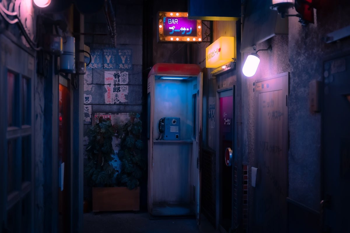 a dark alley with a phone booth and neon lights