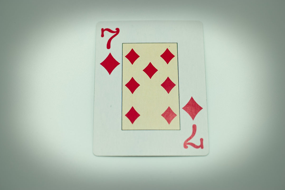 a red and white playing card on a white surface