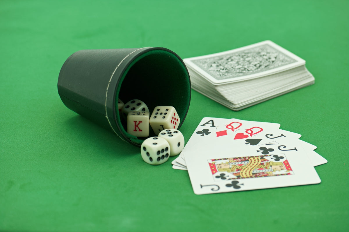 a green table with playing cards and dice