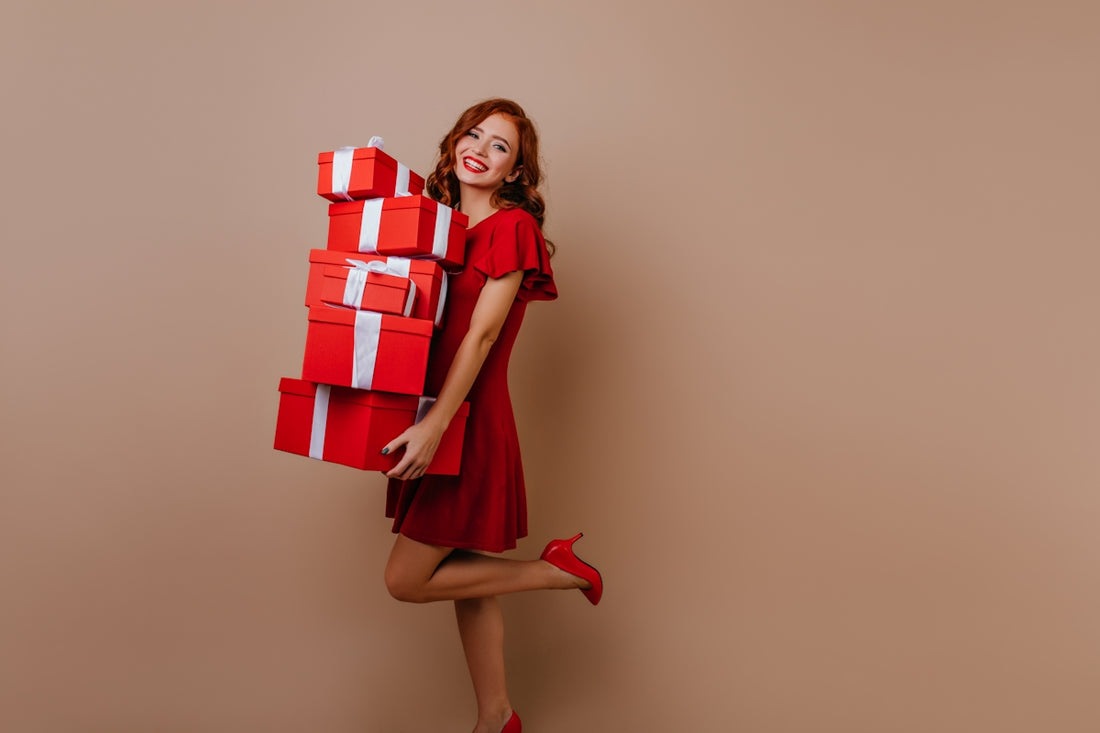 a woman in a red dress holding a stack of red and white boxes