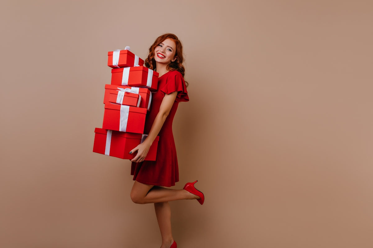 a woman in a red dress holding a stack of red and white boxes
