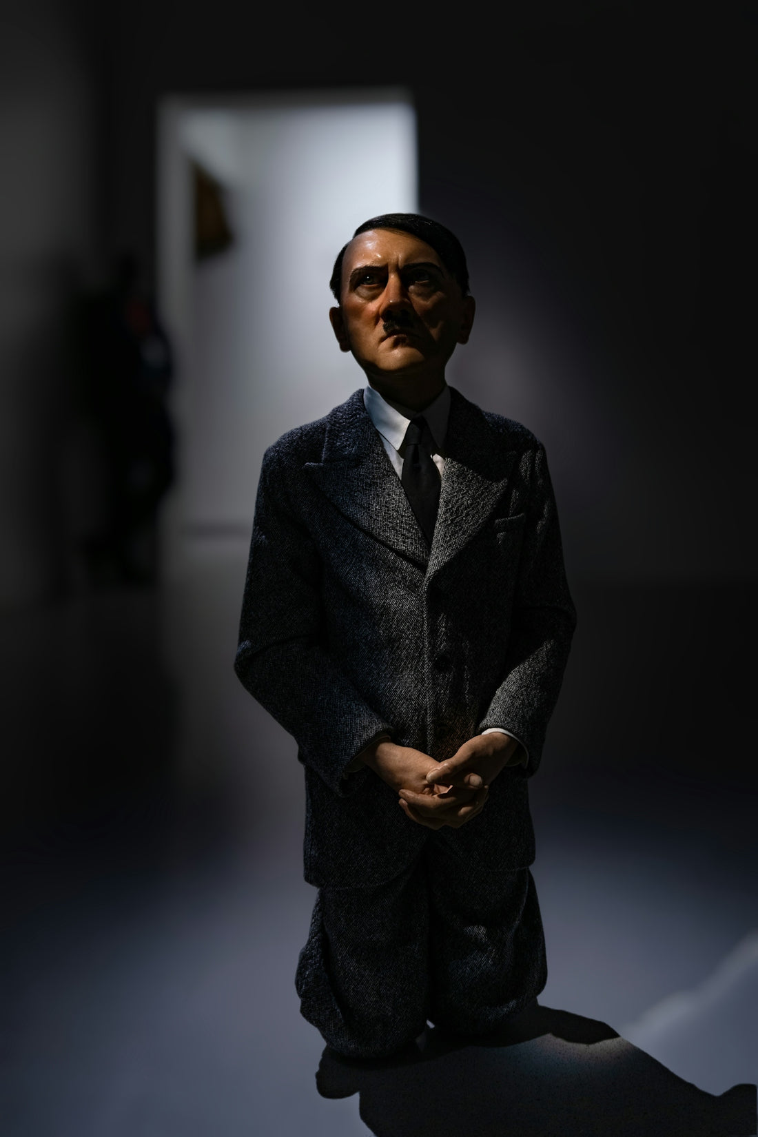 A man in a suit and tie standing in a dark room