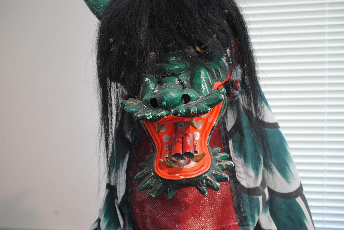 A statue of a demon with a red mask on