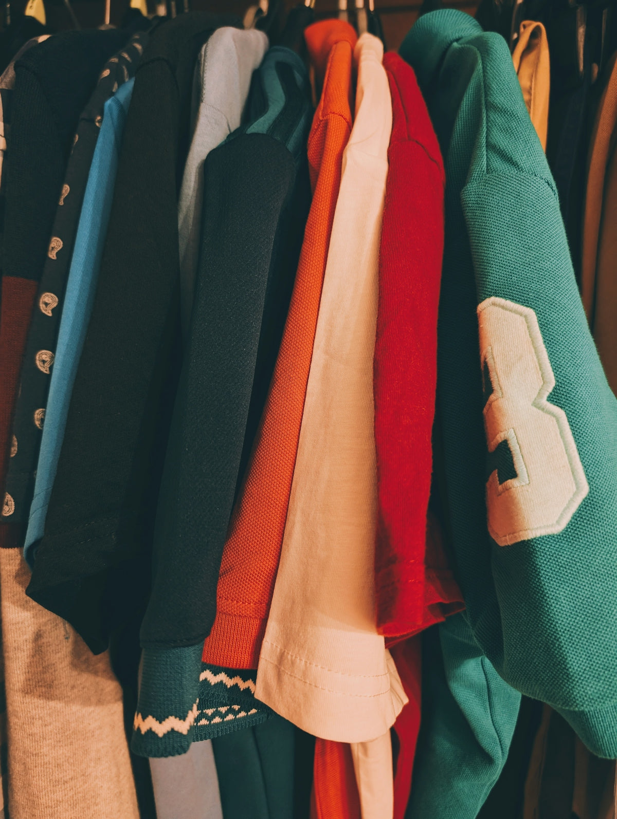 Colorful hoodies hang neatly in a closet.
