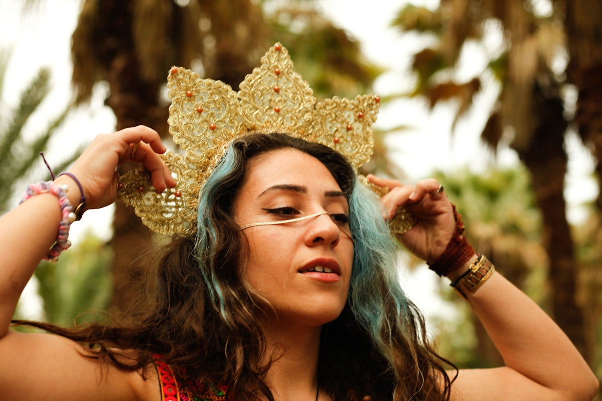 Woman wearing a golden crown and blue hair.