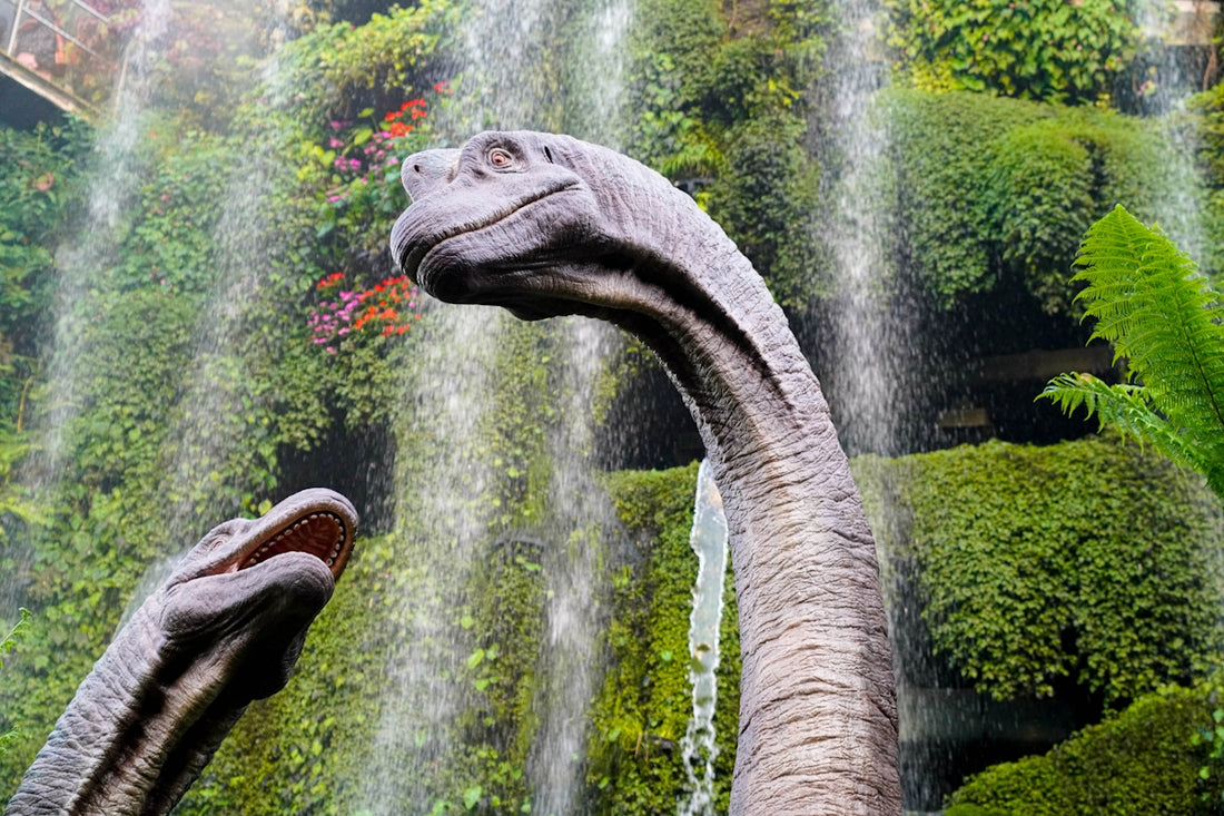 Dinosaurs enjoying a waterfall in a lush garden.