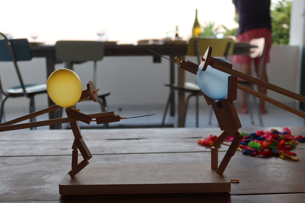 Two stick figures are having a water balloon fight.