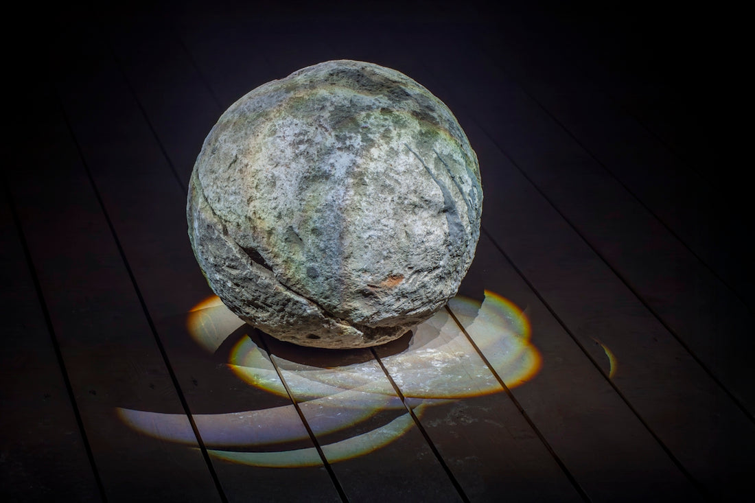 A weathered, round stone rests on a wooden surface.