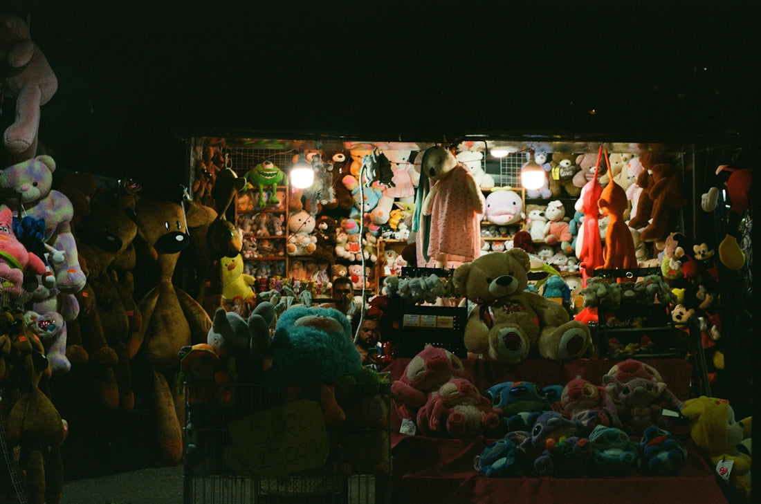 Stuffed animals displayed at a brightly lit night market stall.