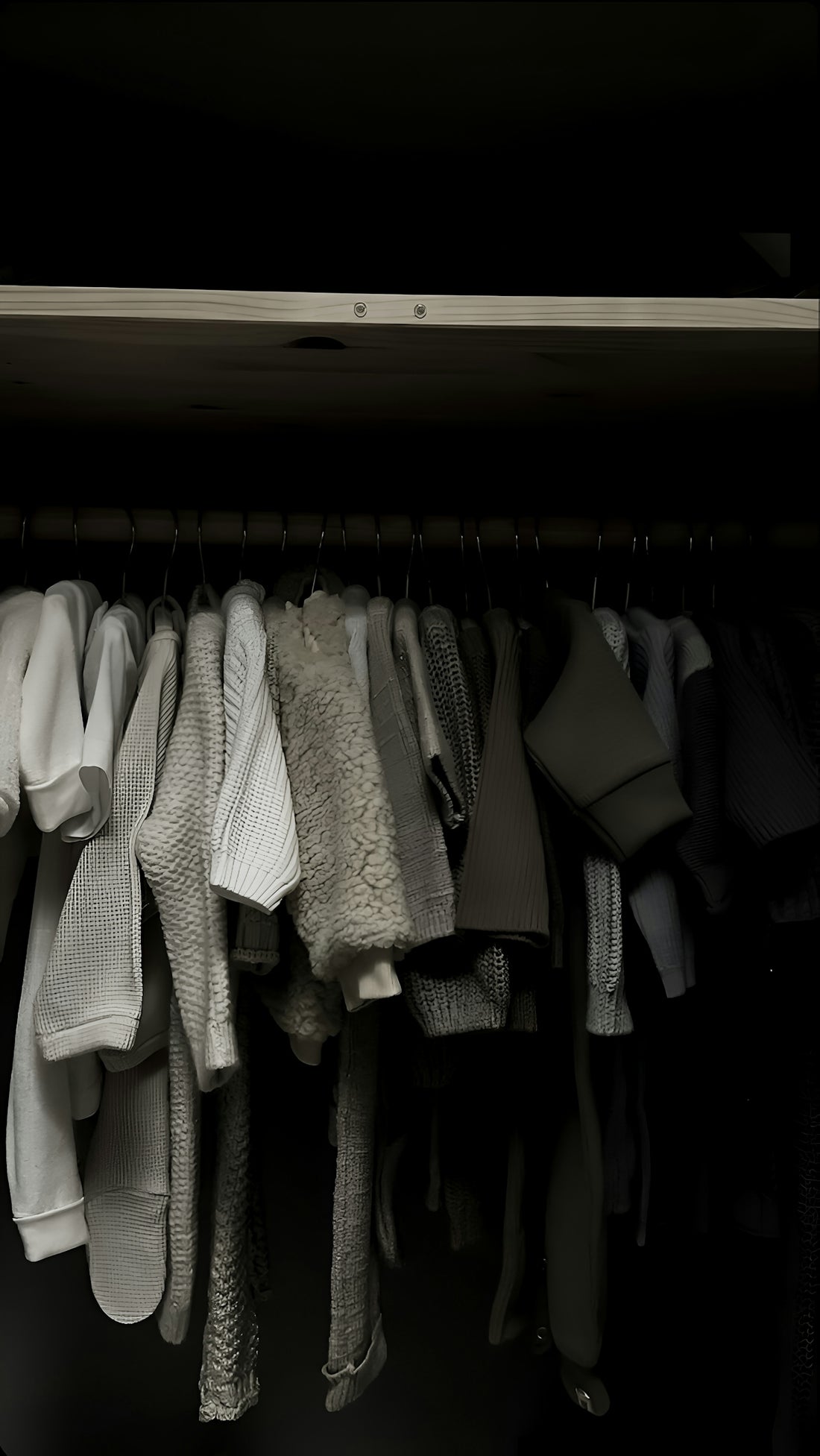 Baby clothes hanging in a dark closet