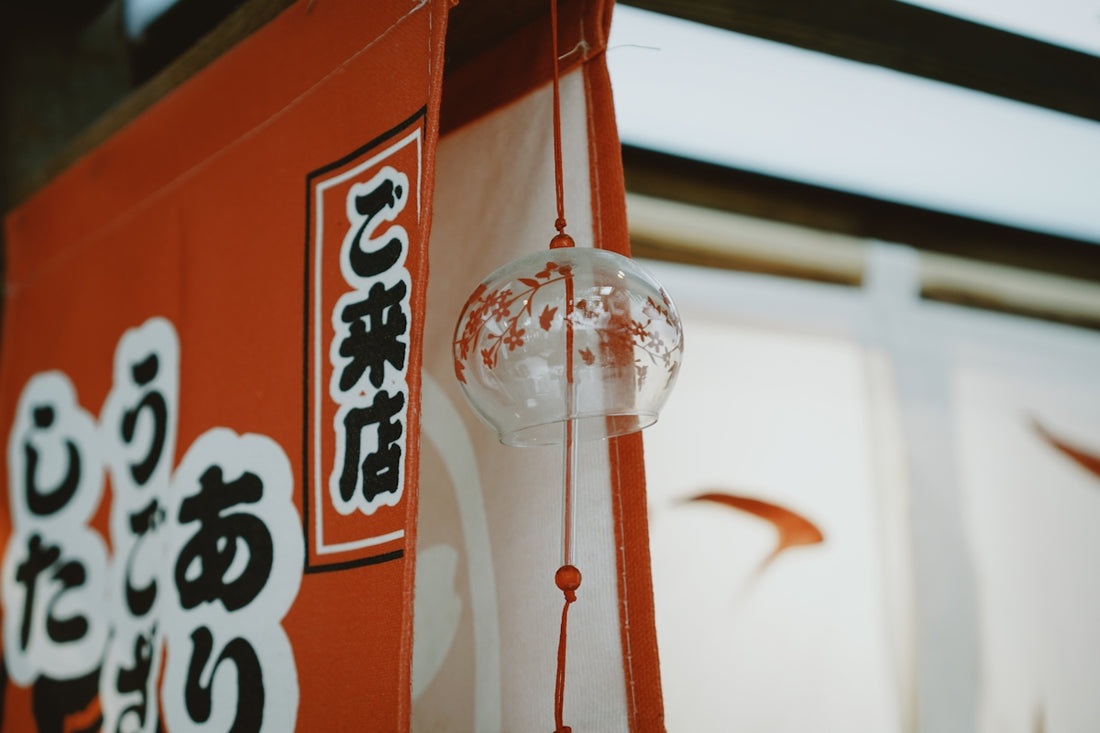 Glass wind chime hangs near red japanese banner